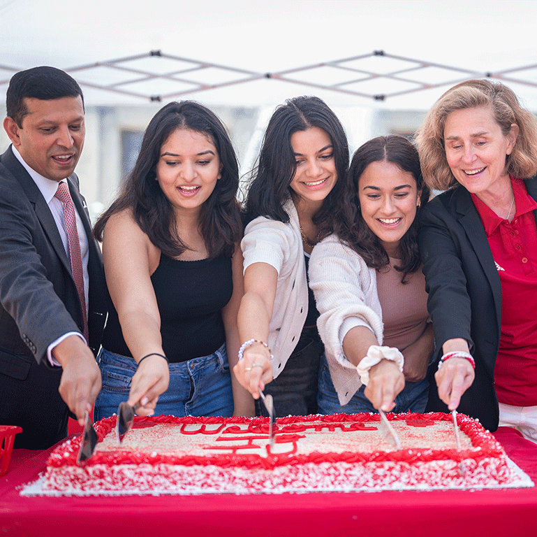 President Whitten, Provost Shrivastav and three students cut a cake on the first day of school.