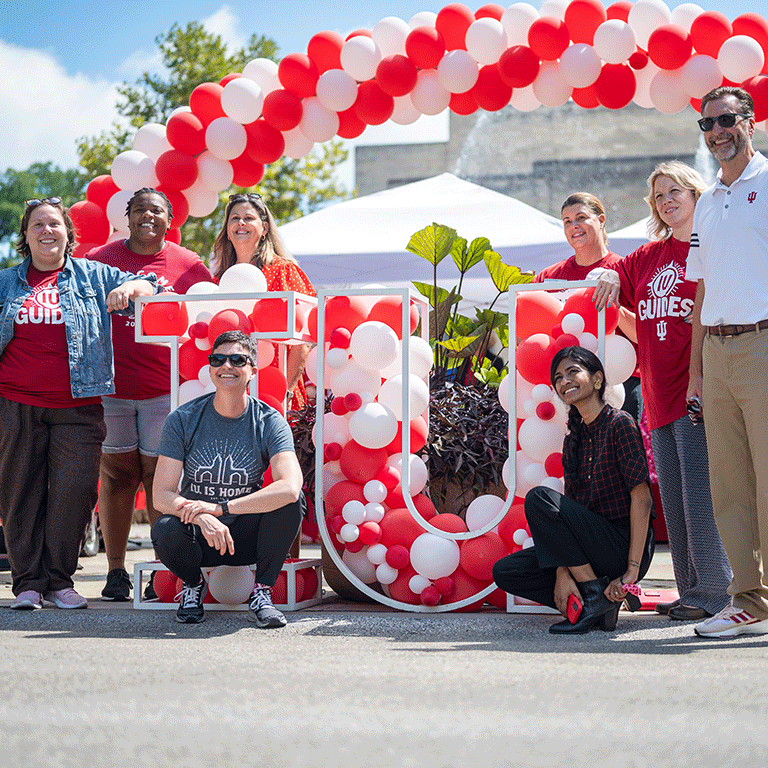 A group poses around an IU balloon structure at the first day of school celebration.