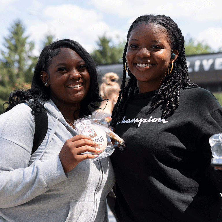 Two female students hold up cookies celebrating the start of school.